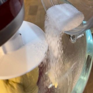 Una persona sta versando lo zucchero in un frullatore.