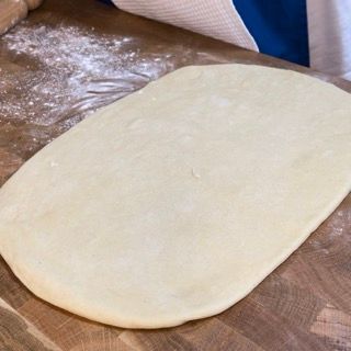 Un pezzo di pasta è appoggiato su un tagliere di legno