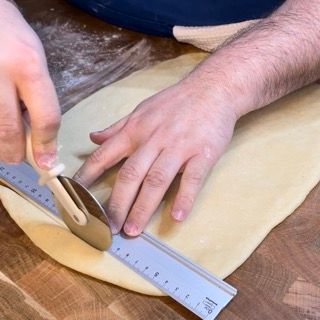 Una persona che misura un pezzo di pasta con un righello