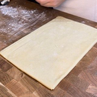 Un pezzo di pasta è appoggiato su un tagliere di legno