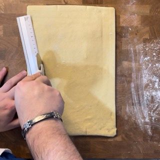 Una persona sta misurando un pezzo di pasta con un righello