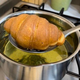 Un croissant è su un cucchiaio in una pentola di zuppa