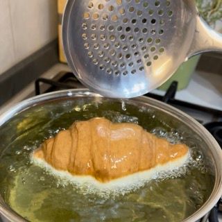 Un croissant viene cucinato in una pentola di acqua bollente