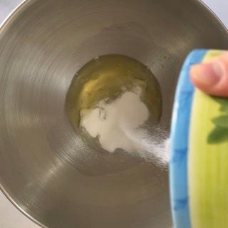 Una persona sta versando lo zucchero in una ciotola di metallo.