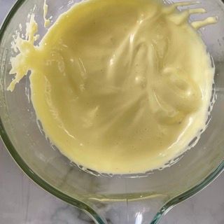 Primo piano di un misurino di vetro pieno di liquido giallo.