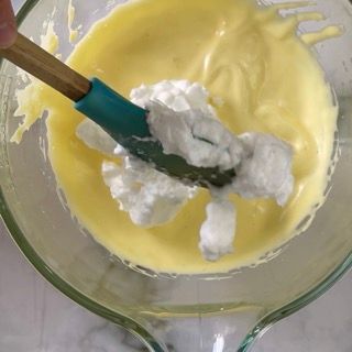 Una persona sta mescolando una ciotola di liquido giallo con una spatola.