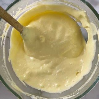 Una ciotola di salsa gialla con un cucchiaio di legno dentro.