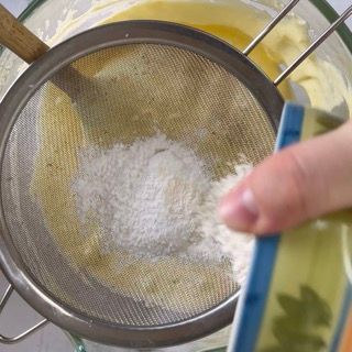 Una persona sta setacciando la farina in una ciotola piena di liquido.