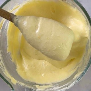 Un cucchiaio di legno è in una ciotola di salsa gialla.