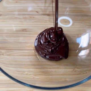 Il cioccolato viene versato in una ciotola di vetro su un tavolo di legno.