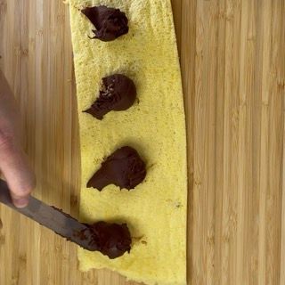 Una persona sta spalmando del cioccolato su un pezzo di mais su un tagliere.