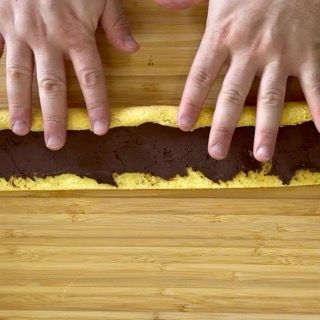 Una persona tiene in mano un pezzo di torta su un tavolo di legno.