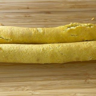 Due rotoli di frittata sono appoggiati su un tagliere di legno.