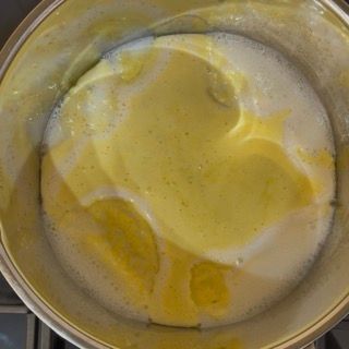 Frusta che mescola la crema sul fuoco