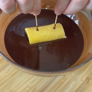 Una persona sta immergendo un pezzo di cibo in una ciotola di salsa al cioccolato