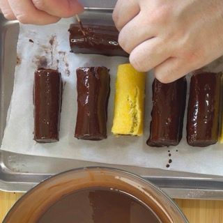 Una persona sta immergendo una barretta di cioccolato in una ciotola di salsa al cioccolato