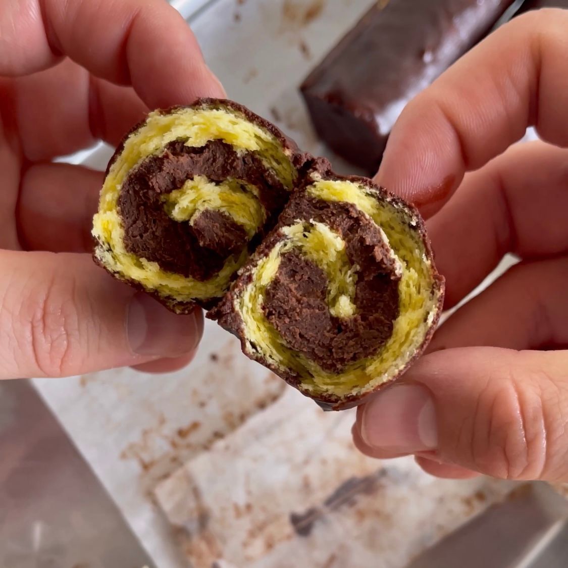 Una persona tiene in mano un pezzo di torta al cioccolato tagliato a metà