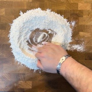 Una persona sta facendo un cerchio di farina su un tavolo di legno