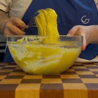 Una persona con un grembiule blu sta mescolando qualcosa in una ciotola