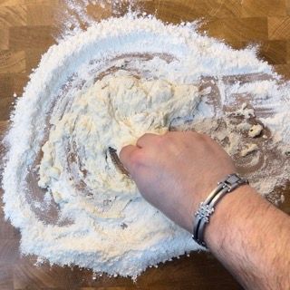 Una persona sta mescolando la farina su un tavolo di legno