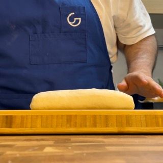 Una persona che indossa un grembiule blu con la lettera g sopra