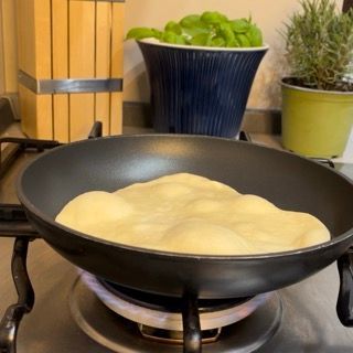 Una pentola di cibo sta cuocendo su un fornello con piante in vaso sullo sfondo