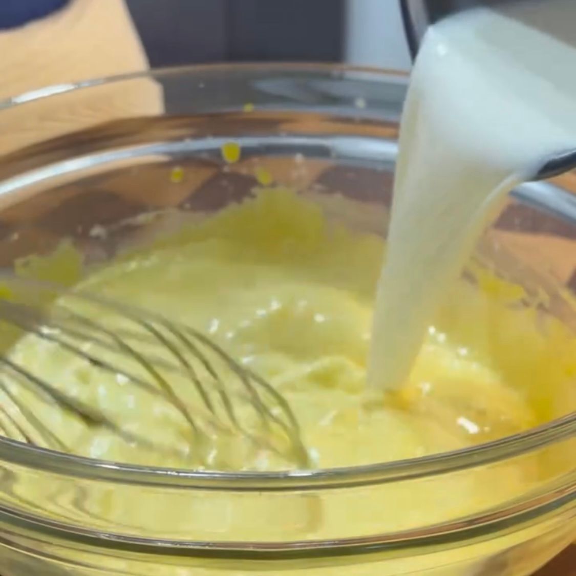 Una frusta viene utilizzata per mescolare un liquido giallo in una ciotola di vetro