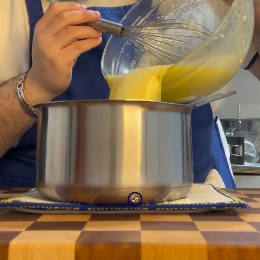 Una persona sta versando del liquido in una pentola con una frusta