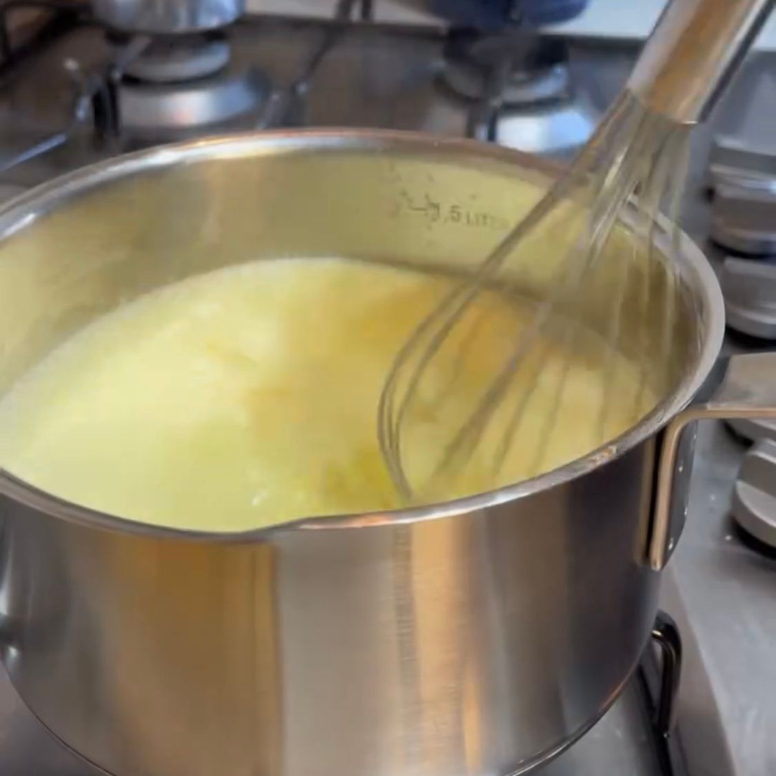 Una pentola di liquido giallo con una frusta dentro