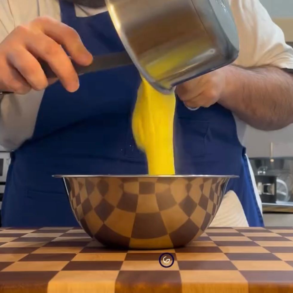 Una persona sta versando del liquido giallo in una ciotola a scacchi