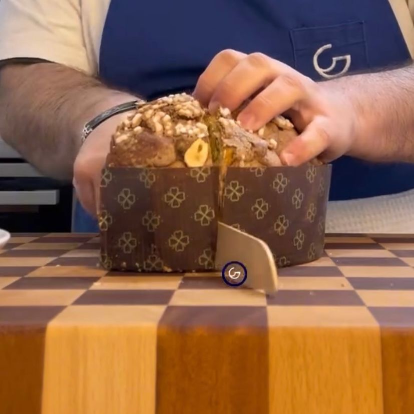 Una persona sta tagliando una torta su un tagliere di legno