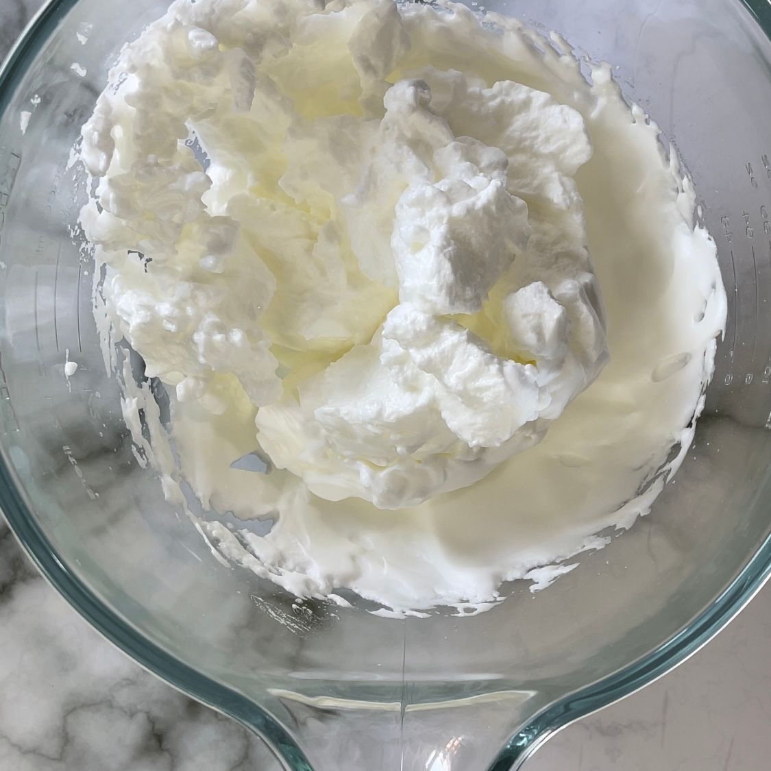La panna montata è in una ciotola di vetro su un tavolo.