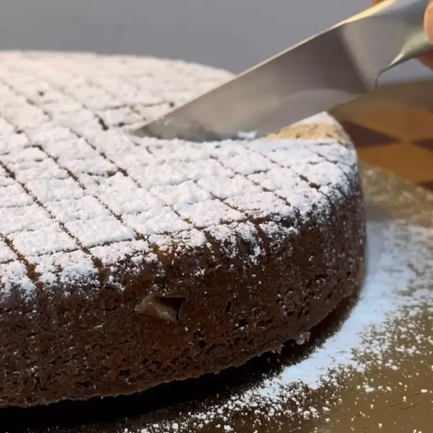 Torta Caprese originale appena sfornata, con la sua tipica crosticina crepata e una spolverata di zucchero a velo.