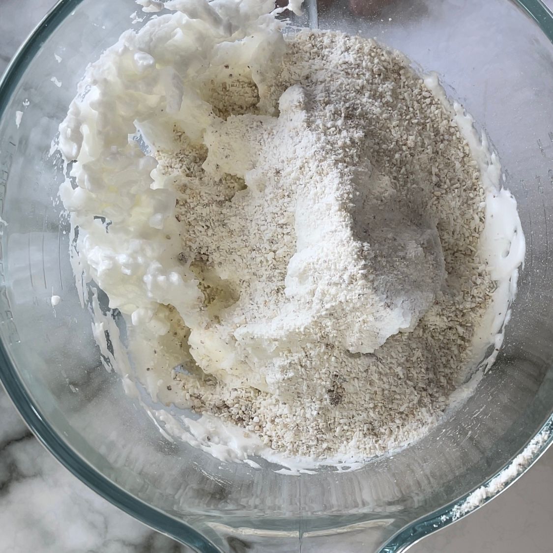 Un primo piano di una tazza graduata piena di ingredienti in polvere