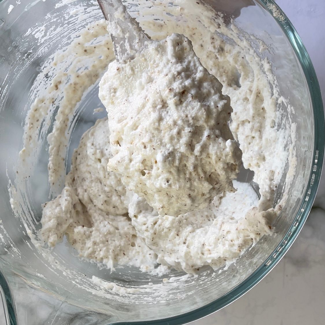 Una ciotola di vetro piena di una sostanza bianca con un cucchiaio dentro.