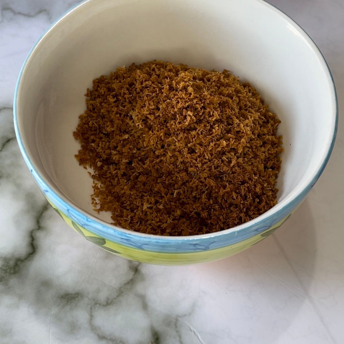 Una ciotola piena di polvere marrone è appoggiata su un tavolo.