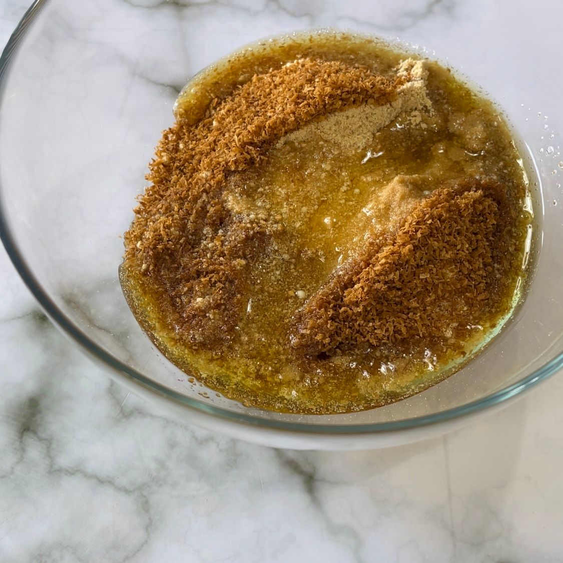 Una ciotola di vetro piena di un liquido giallo e polvere marrone.