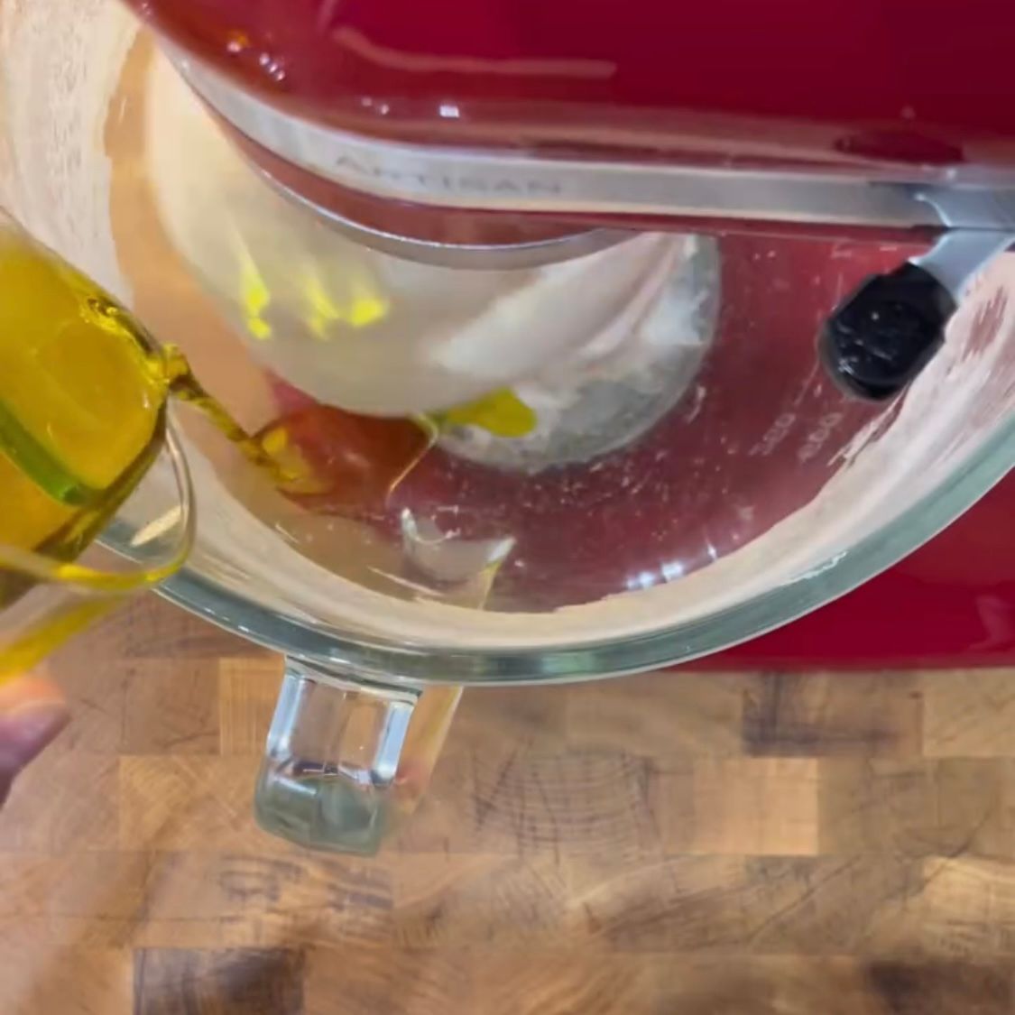 Una persona sta versando l'olio in una ciotola di vetro