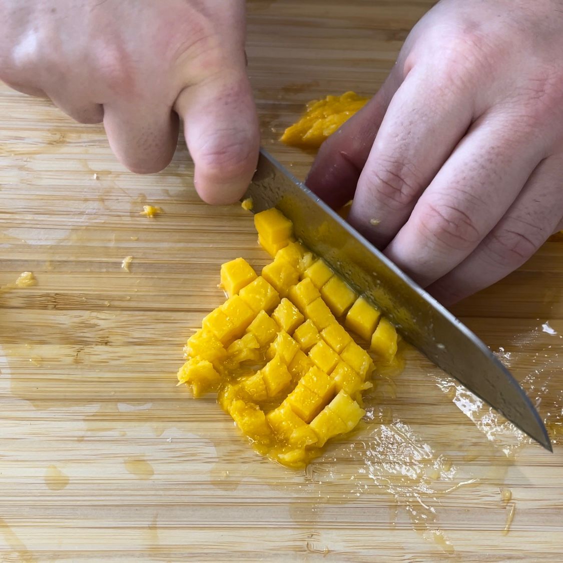 Una persona sta tagliando un pezzo di mango su un tagliere