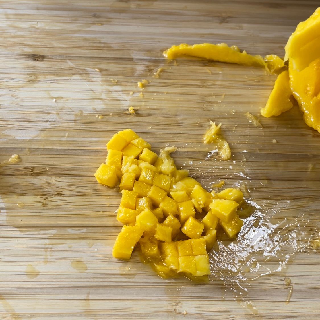 Un mango tagliato a fette è appoggiato su un tagliere di legno.