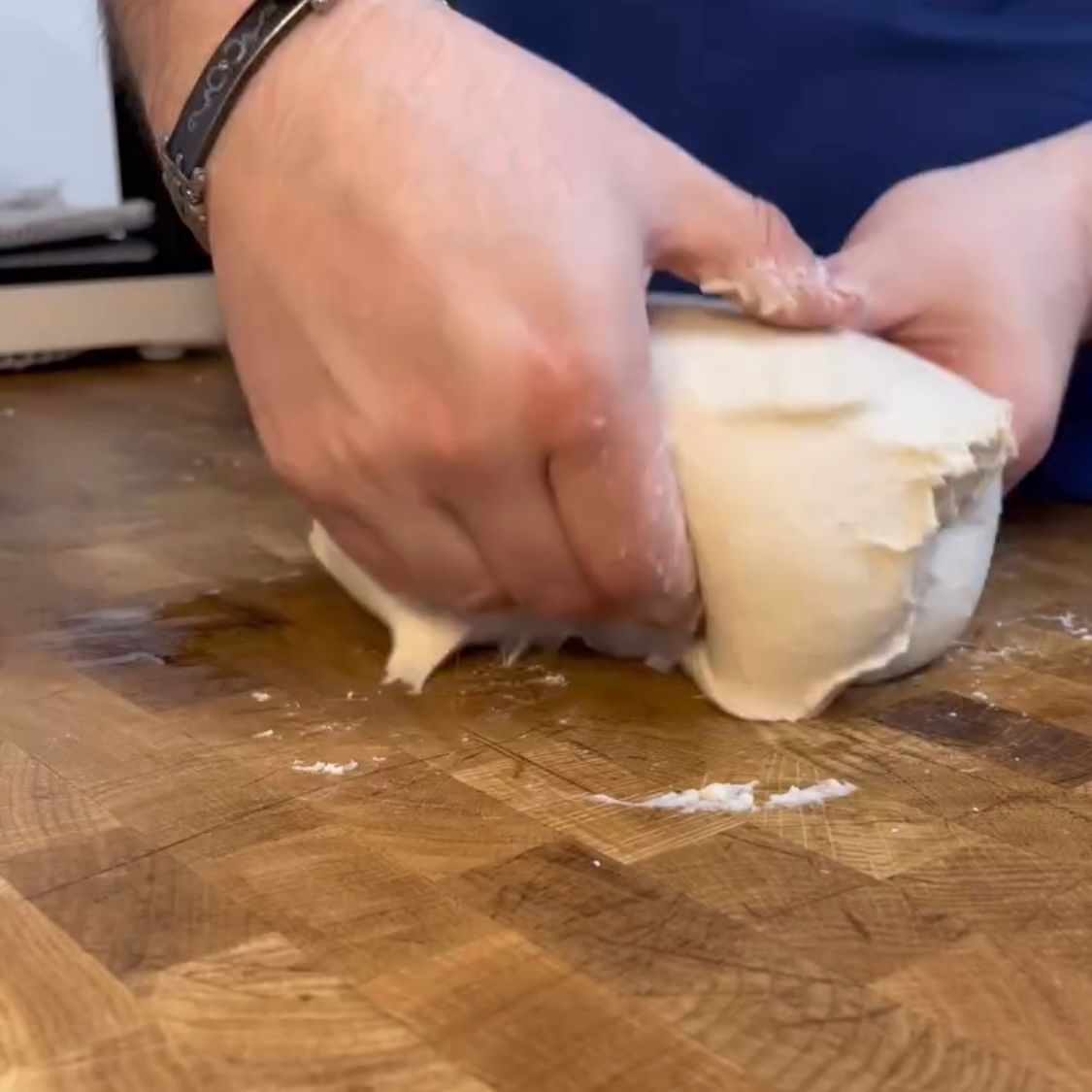Una persona sta impastando la pasta su un tagliere di legno