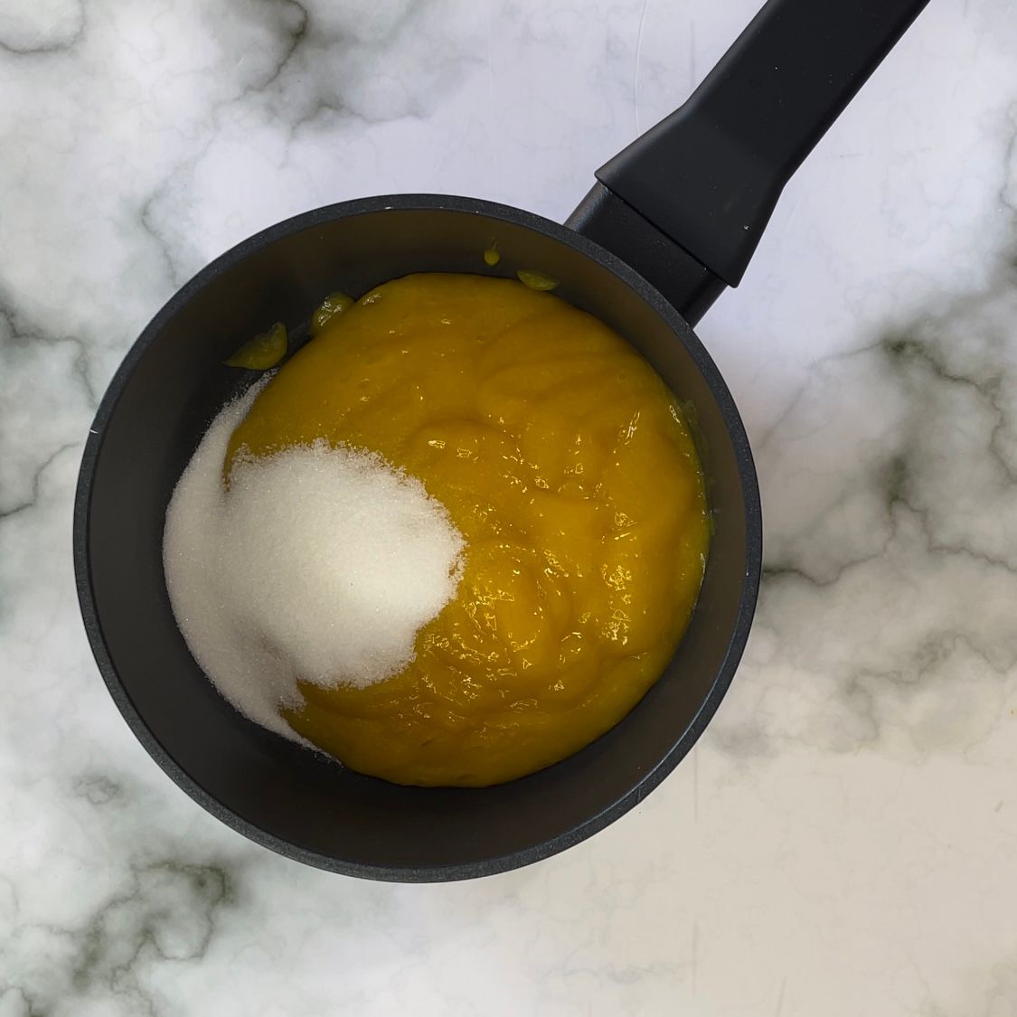 Una pentola di salsa gialla con zucchero dentro
