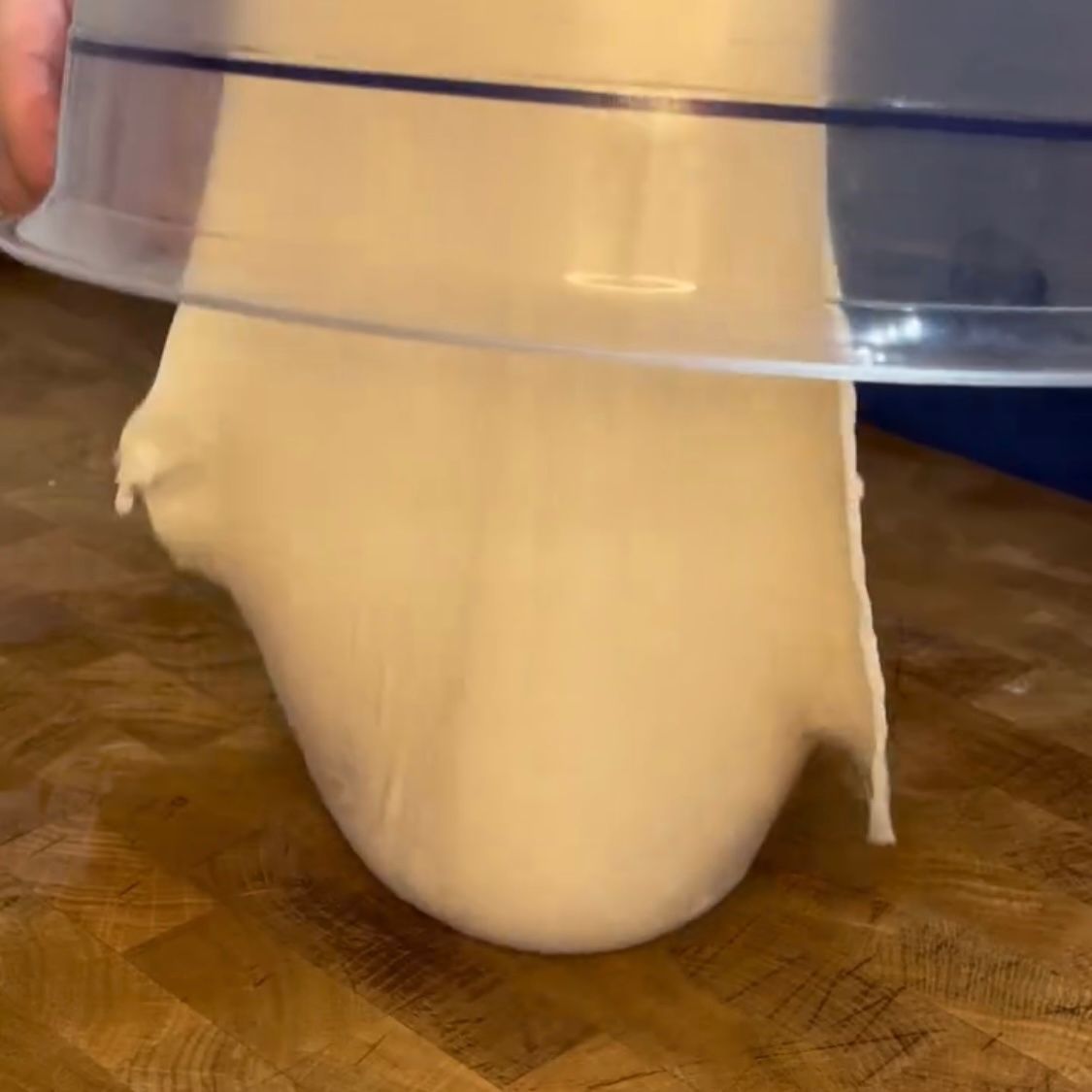 Una persona tiene in mano una ciotola di pasta su un tavolo di legno.