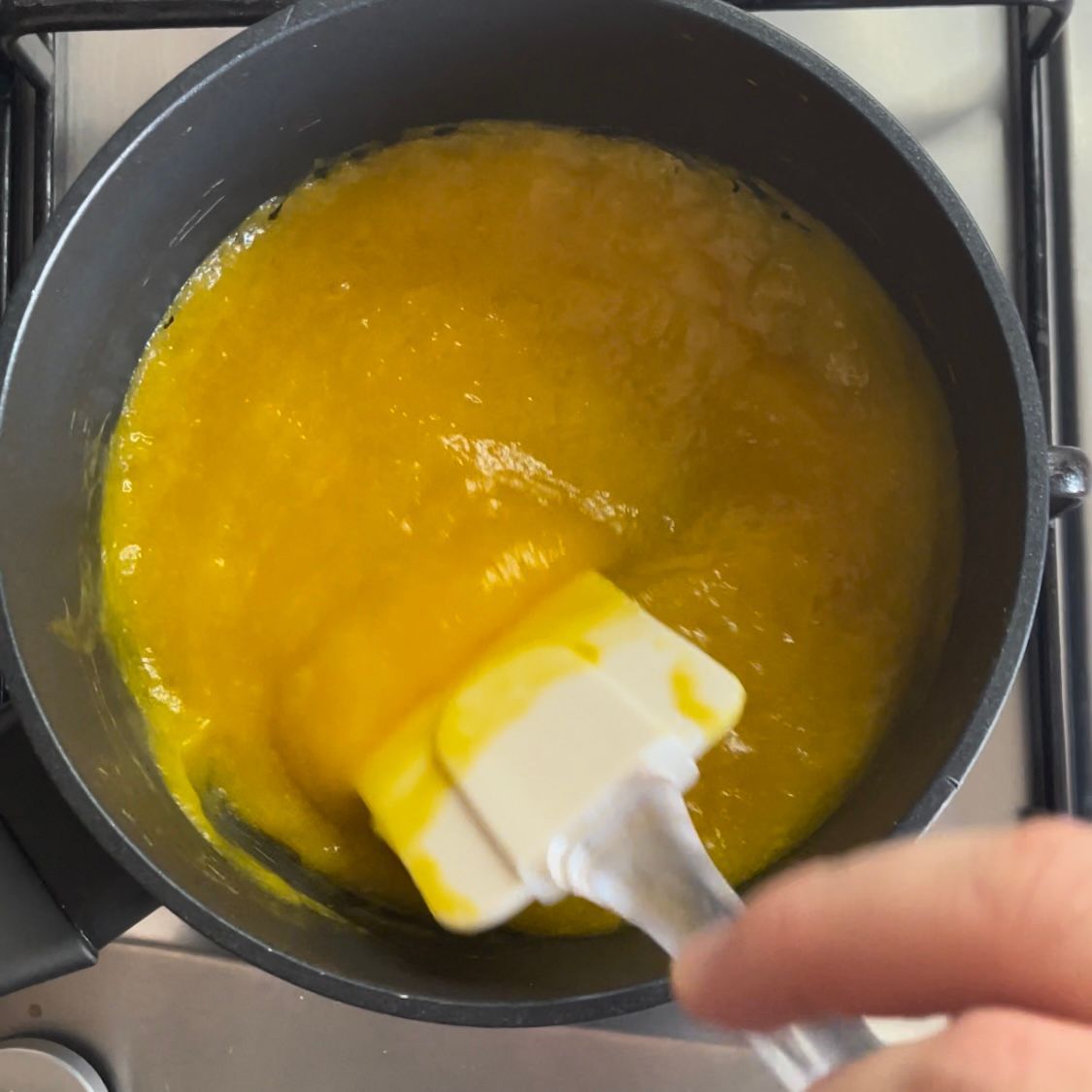 Una persona sta mescolando un liquido giallo con una spatola