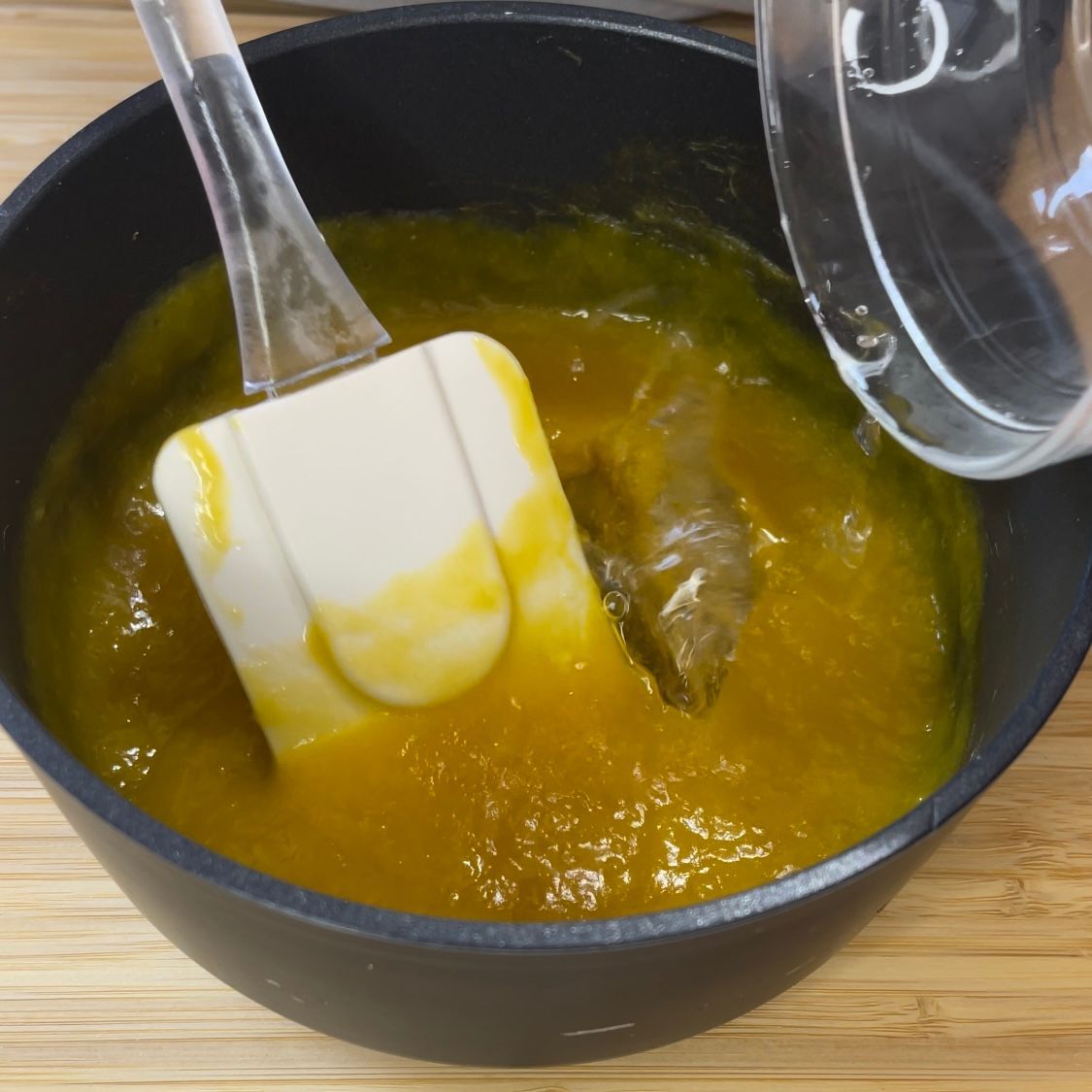 Una ciotola di liquido giallo con una spatola dentro