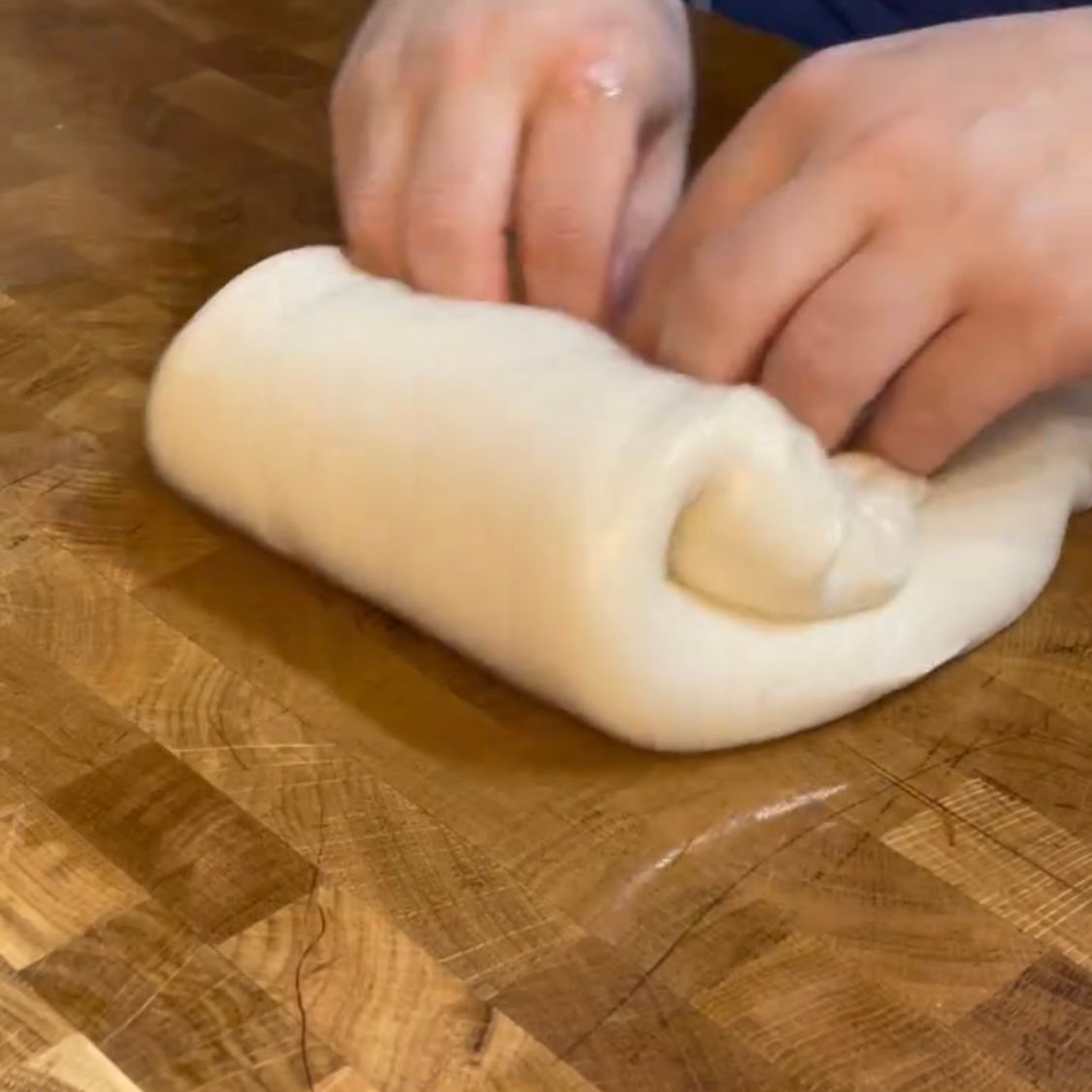 Una persona sta impastando la pasta su un tagliere di legno
