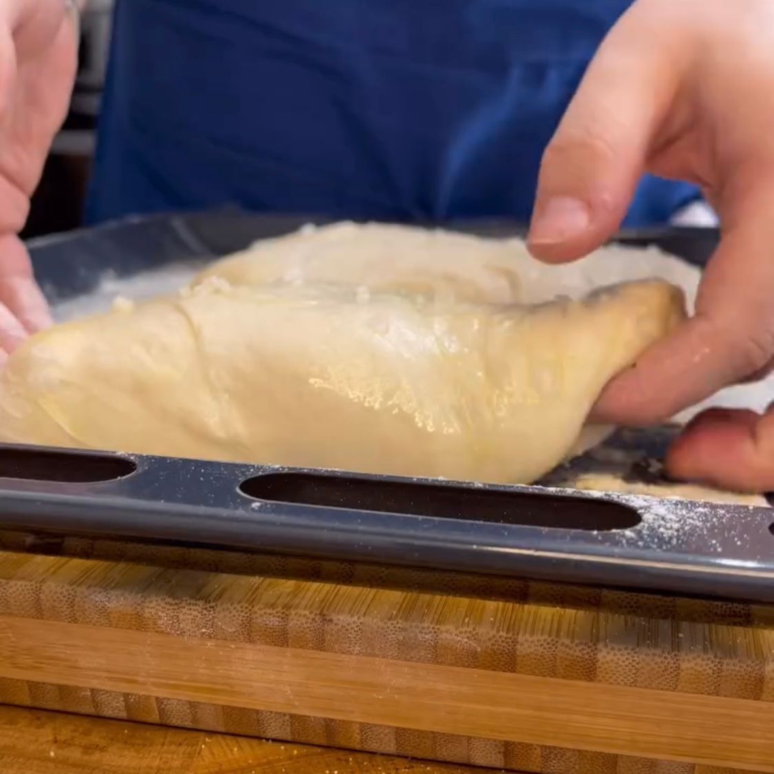 Una persona tiene in mano un pezzo di pasta su una padella.
