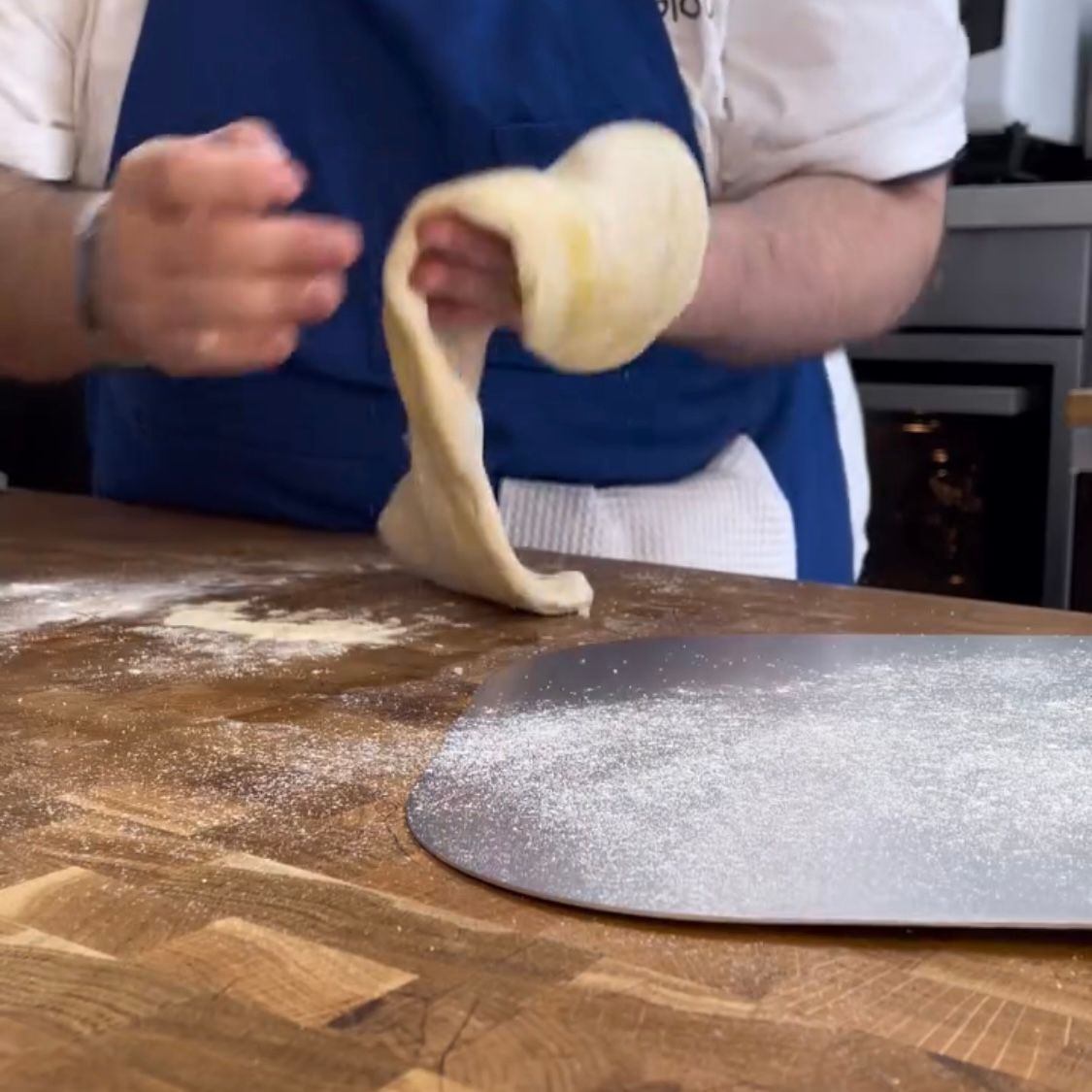 Una persona sta impastando la pasta su un tavolo di legno