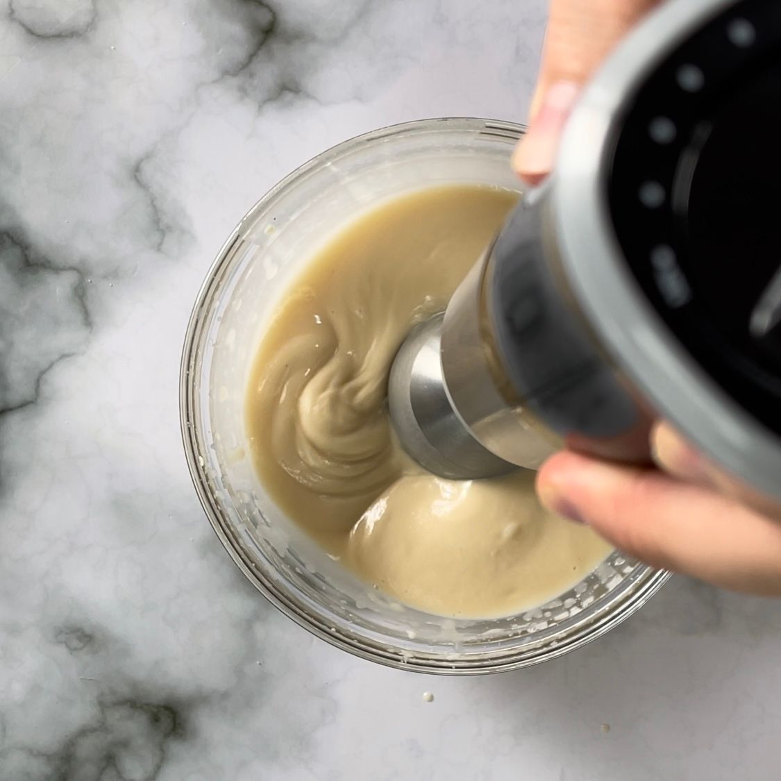 Una persona sta mescolando qualcosa in una ciotola con un frullatore.