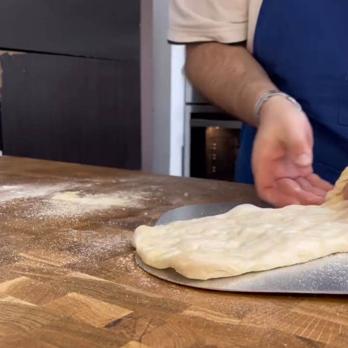 Una persona sta stendendo la pasta su una teglia per pizza